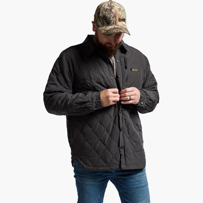 Man wearing a black quilted jacket and camouflage cap on a white background